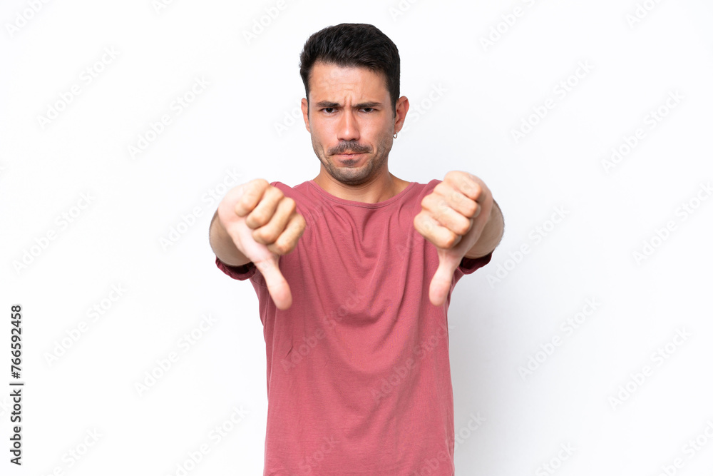 Young handsome man over isolated white background showing thumb down with two hands Young handsome man over isolated white background showing thumb down with two hands