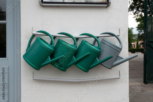 Watering cans hanging on a wall at the entrance to a garden
