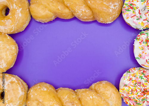 Flat Lay Top View of a variety of donuts forming a border around a vibrant purple background.