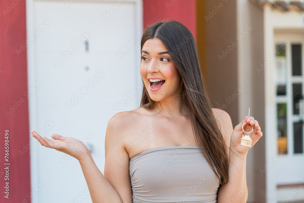 girl holding home keys at outdoors with surprise facial expression girl holding home keys at outdoors with surprise facial expression