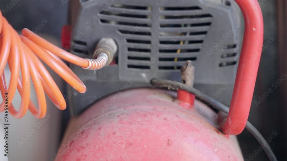 Dusted air compressor with spiral cable in workshop, machine with air pressure used in industrial purposes