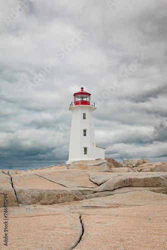 Lighthouse on the rocks on a cloudy sky