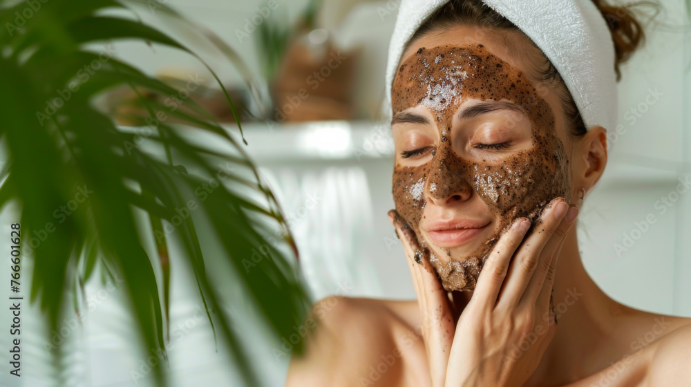 A woman applies a mask to her face while wearing a white towel. She smiles and enjoys the process. Skin care concept. A woman applies a mask to her face while wearing a white towel. She smiles and enjoys the process. Skin care concept.