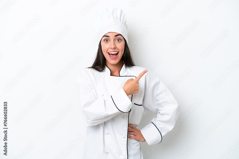 Young chef woman over white background surprised and pointing side Young chef woman over white background surprised and pointing side