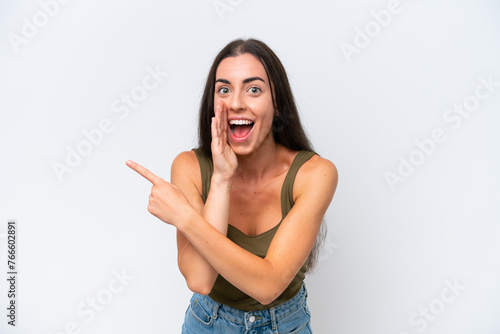 Young caucasian woman isolated on white background pointing to the side to present a product and whispering something