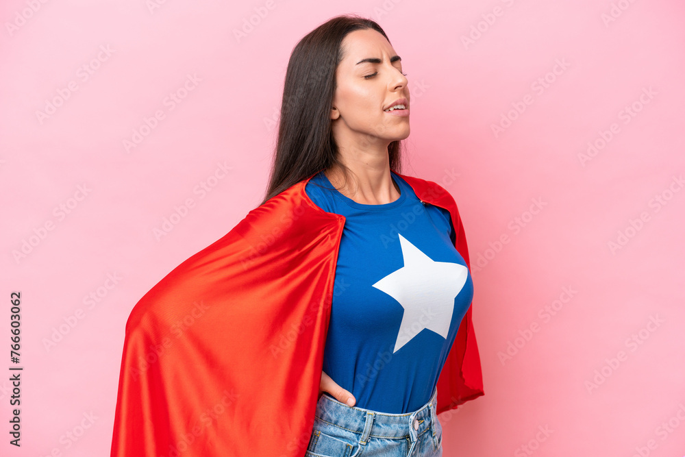 Super Hero Caucasian woman isolated on pink background suffering from backache for having made an effort Super Hero Caucasian woman isolated on pink background suffering from backache for having made an effort
