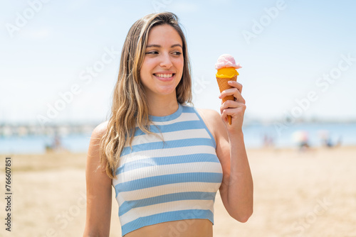 Young pretty woman with a cornet ice cream at outdoors with happy expression