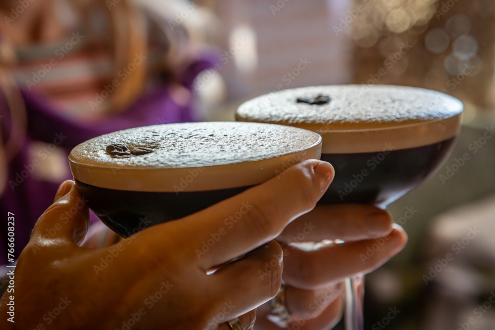 Espresso martini cocktails being held at a party - obrazy, fototapety, plakaty 