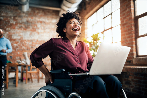 African American businesswoman in a wheelchair laughs while working on her laptop in a creative office space, embodying success and accessibility.   © InputUX