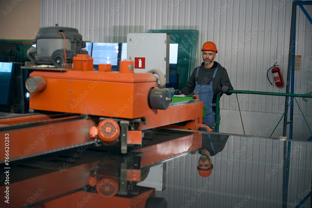 Man uses an automatic glass cutting table in window production