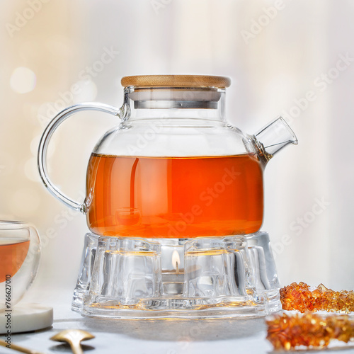 tea concept, glass teapot on teapot stand, on white background. Brewing and Drinking tea.