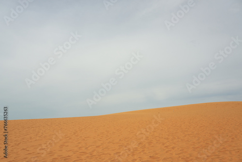 Sand dune in the desert with clouds in the background.