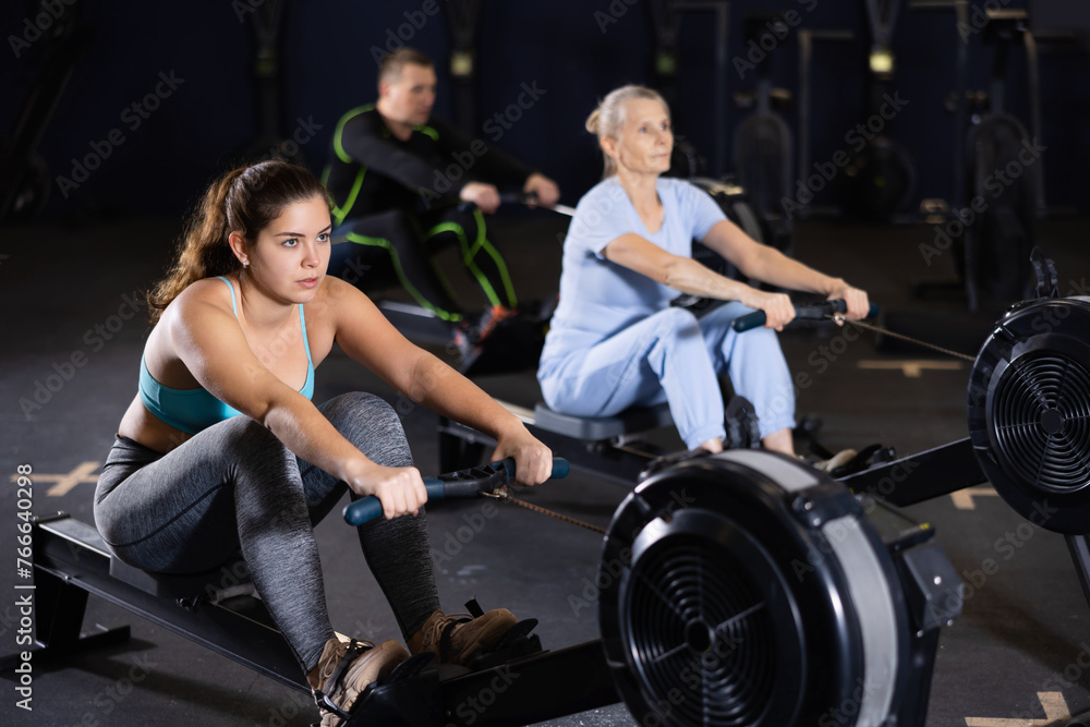 Fototapeta premium Athlete woman works on the rowing simulator in gym