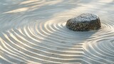 The image is a close-up of a Zen garden with a single rock in the center. The sand is raked in a circular pattern around the rock.