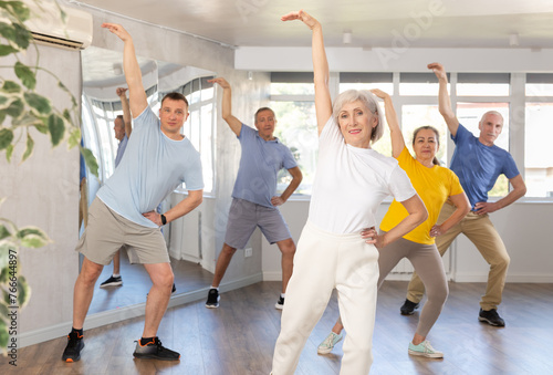 Elderly woman dances energetic modern dances in group in studio