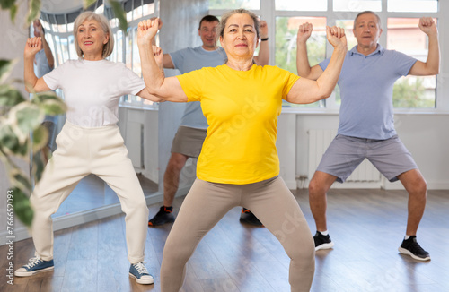 Group of aged people rehearsing sports dance in dance hall