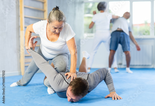 Aggressive old woman twisting her opponent's arm during self-defense classes