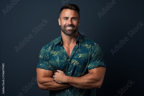 Portrait of a handsome man smiling with arms crossed over dark background
