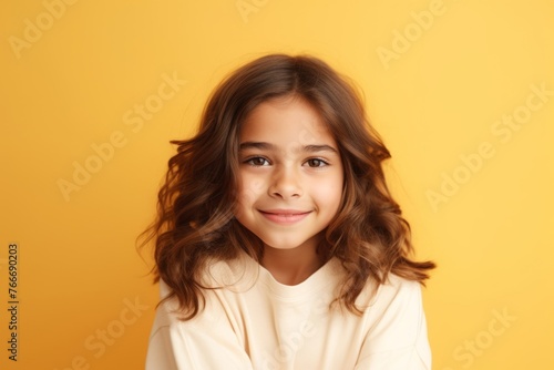 Portrait of a cute little girl with long curly hair on a yellow background