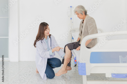 Asian doctor holding leg and use hand point to knee of old stroke patient,  they training to rehab muscle  in hospital, Knee Replacement, Osteoarthritis of the Knee, elderly rehabilitation clinic