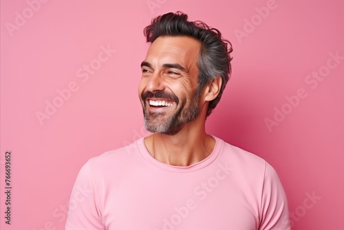 Portrait of a handsome middle-aged man smiling against pink background © Inigo