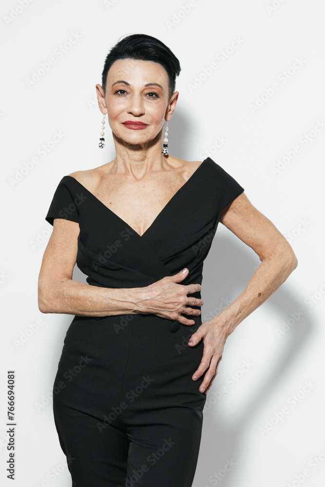 Confident mature woman in black jumpsuit posing with hands on hips for camera in studio photo shoot Confident mature woman in black jumpsuit posing with hands on hips for camera in studio photo shoot