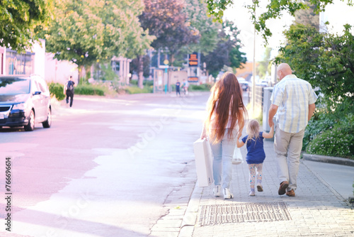 man and woman with child, happy family together walks along city street, blurred overexposed image, concept of family serene happiness, cherishing life's moments, urban landscape photo
