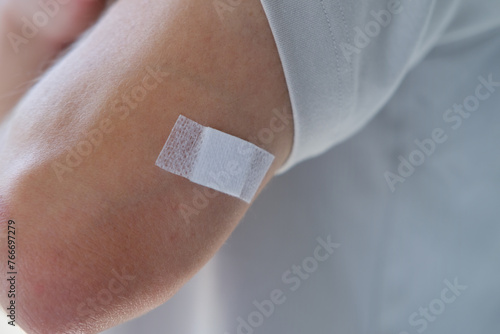 young man after injection, forearm patient close-up, white plaster on hand, medical vaccine against virus COVID-19, Seasonal Influenza Vaccine, vaccination for travel photo