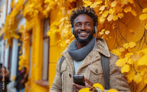 A man with a beard and headphones is smiling and holding a cell phone