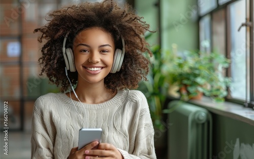 A woman with curly hair is smiling and holding a cell phone