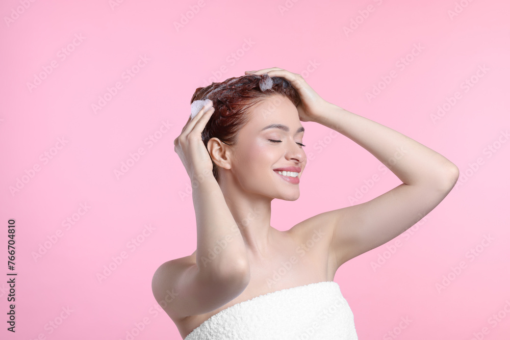 Happy young woman washing her hair with shampoo on pink background Happy young woman washing her hair with shampoo on pink background