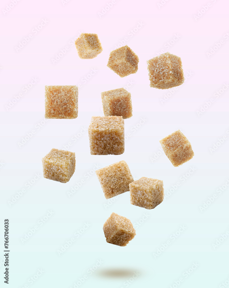 Brown cane sugar cubes falling on color gradient background Brown cane sugar cubes falling on color gradient background