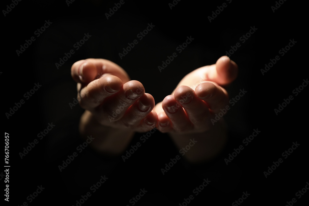 Religion. Woman with open palms praying on black background, closeup Religion. Woman with open palms praying on black background, closeup