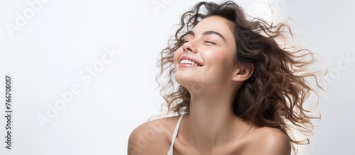 A woman with surfer hair and blonde curly locks is happily smiling with her eyes closed  enjoying the wind blowing through her hair during a travel event