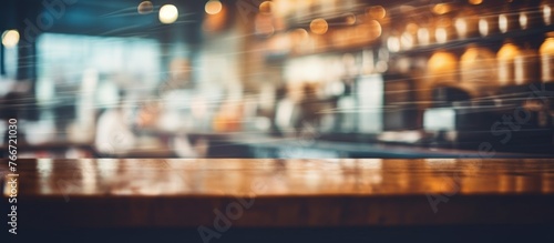 A city bar captured in a blurry image, featuring a wooden table in the foreground. An event display device rests on the table, showcasing a rectangular font © AkuAku