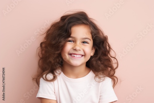 Portrait of a smiling little girl with long curly hair on a pink background