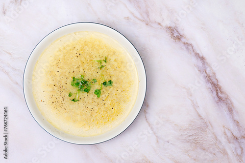 Instant chicken bone noodle soup in a white ceramic bowl isolated on white marble background. Parsley garnish. photo