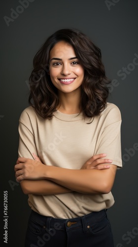 Portrait of young Mexican woman with pleasant smile and arms crossed isolated on gray wall with copy space Beautiful young woman with folded arms looking at camera against gray wall. isolated studio