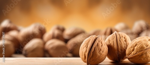A pile of walnuts, a staple food and natural produce, sit on a wooden table. They are versatile ingredients used in various recipes and cuisines, making them a popular choice for finger food snacks © AkuAku