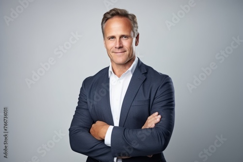 Confident mature businessman with arms crossed, looking at camera and smiling.