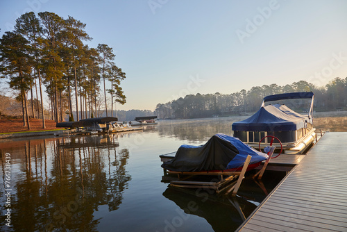 Dock with covered boat and jet ski on a beautiful calm lake in Georgia in springtime