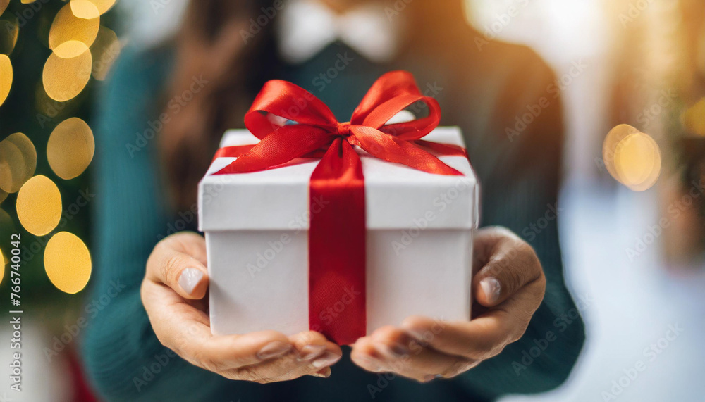 hands presenting gift with red bow, conveying love and celebration on clean background