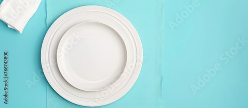 White plate and cotton napkin placed on a blue background. Ideal setting for a food-themed menu or recipe book, featuring a top-down view.