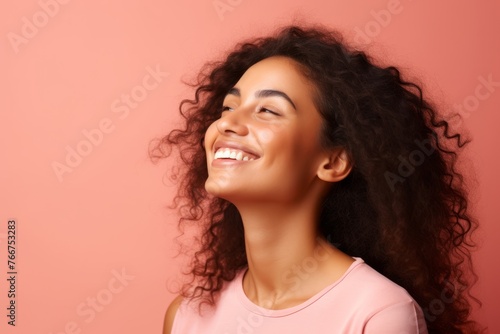 Beautiful young african american woman with long curly hair on pink background