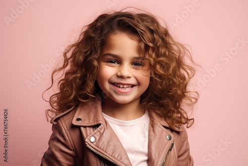 Portrait of a cute little girl with curly hair over pink background