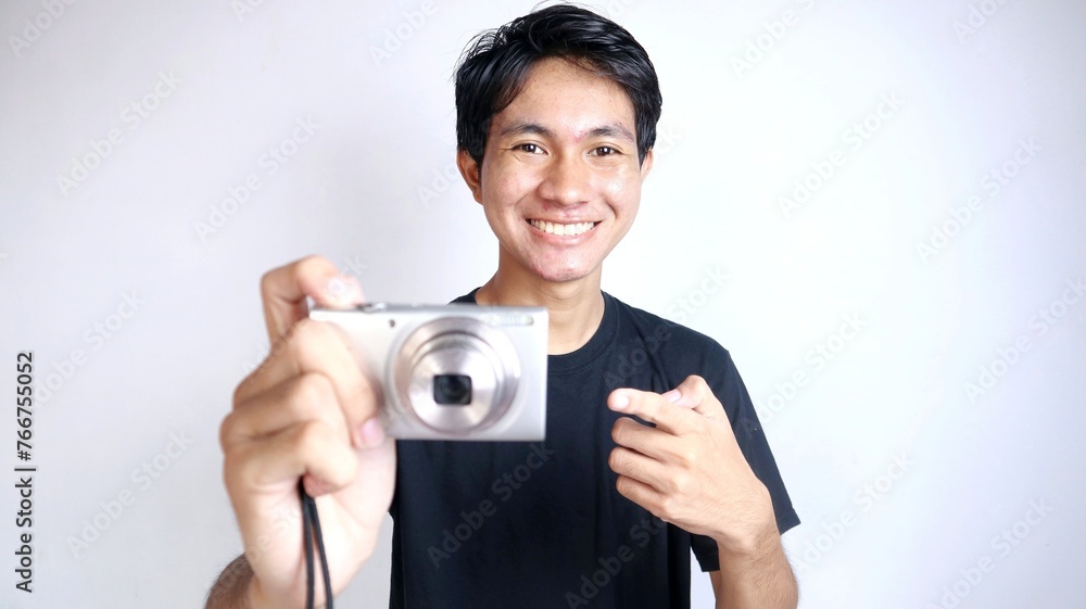 Close-up of young handsome Asian man happily gesturing using camera and pointing forward with isolated white background