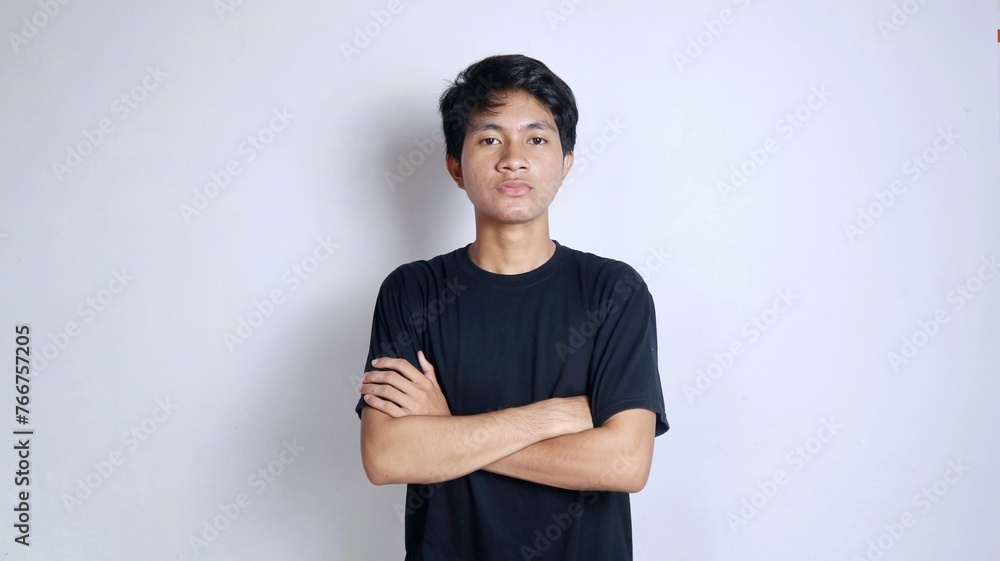 Obraz premium Handsome young Asian man gesturing with crossed arms and wearing a black shirt