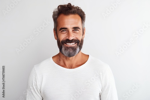 Portrait of handsome mature man looking at camera and smiling while standing against grey background