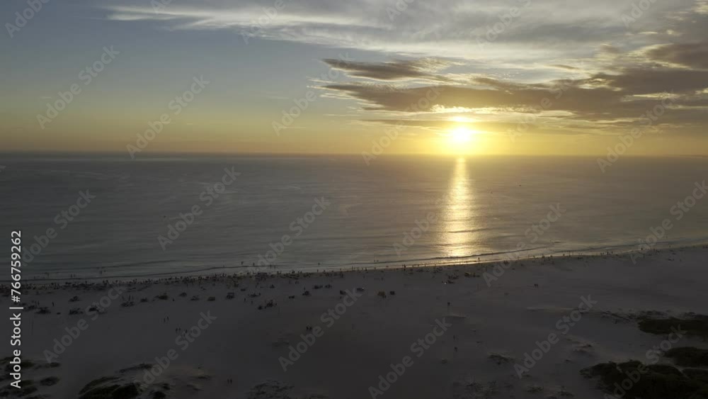 Drone flies from beach to sea toward sunset on water Drone flies from beach to sea toward sunset on water