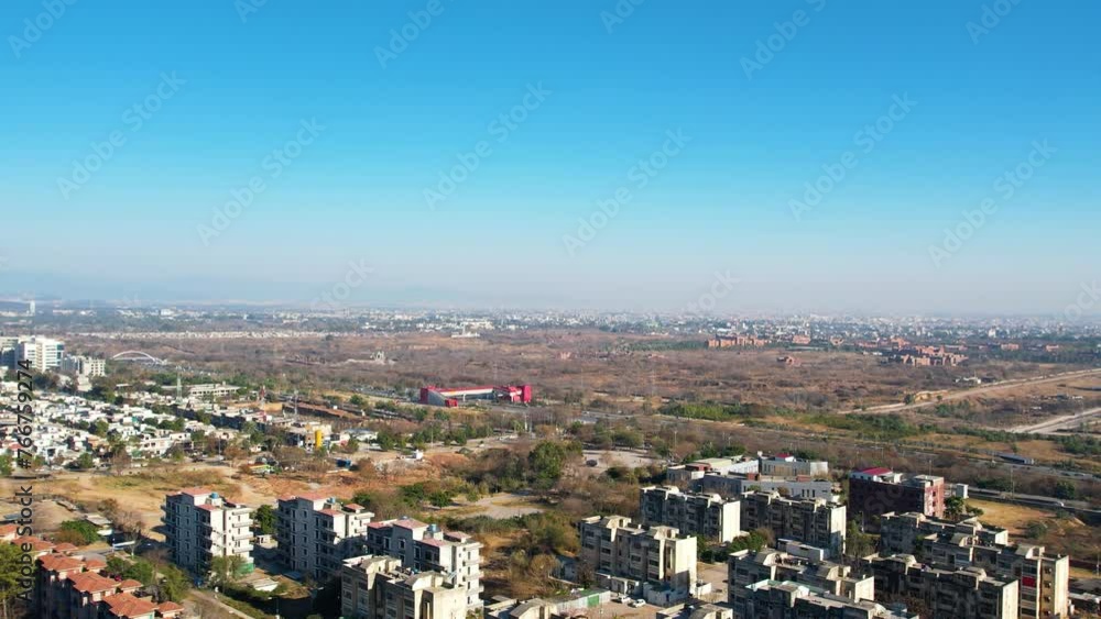 Aerial view of Islamabad cityscape with the skyline towards Rawalpindi with Srinagar highway and Metro station visible behind the residential buildings Aerial view of Islamabad cityscape with the skyline towards Rawalpindi with Srinagar highway and Metro station visible behind the residential buildings